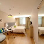 Spacious modern hotel room featuring cozy decor and neutral tones with natural light.