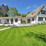 Contemporary house exterior with large manicured lawn and beautiful garden.